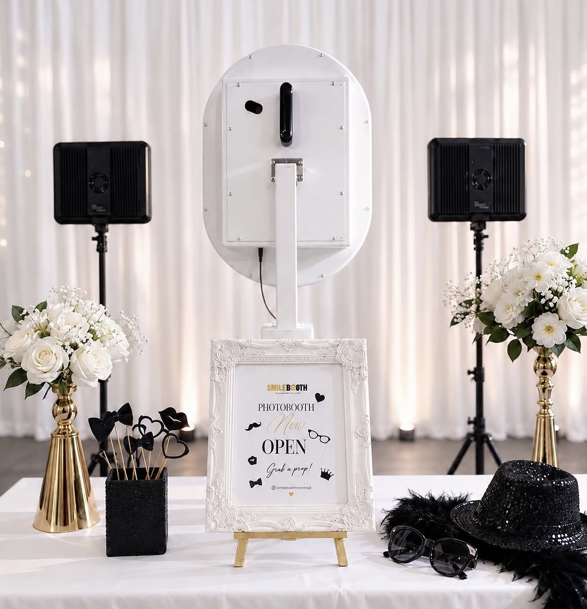 Photobooth station with a welcome sign, flowers, hats and accessories