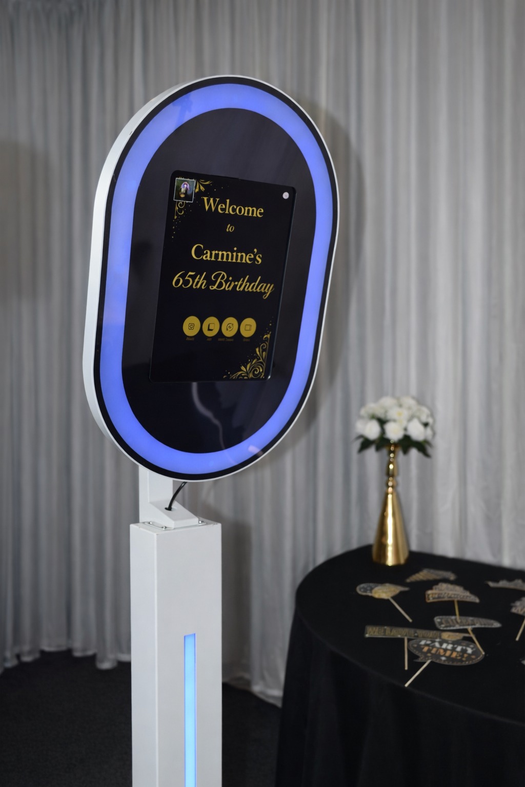 Mirror photobooth illuminated in blue beside a prop table