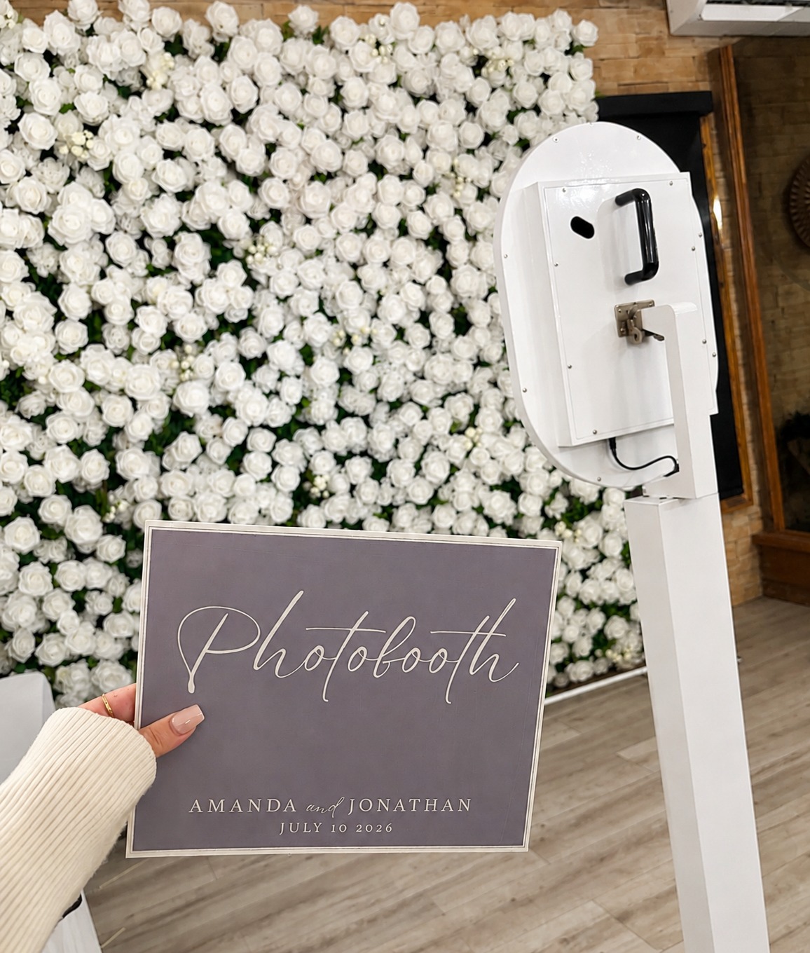 Photobooth in front of a white flower wall with a personalised event sign