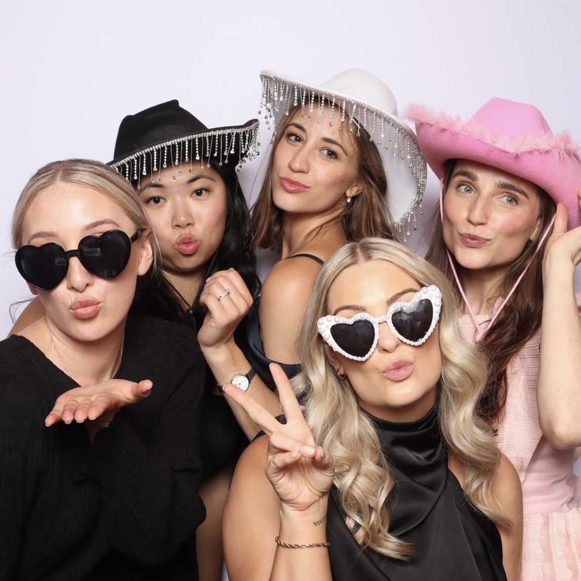 Friends having fun posing together with photobooth hats and sunglasses